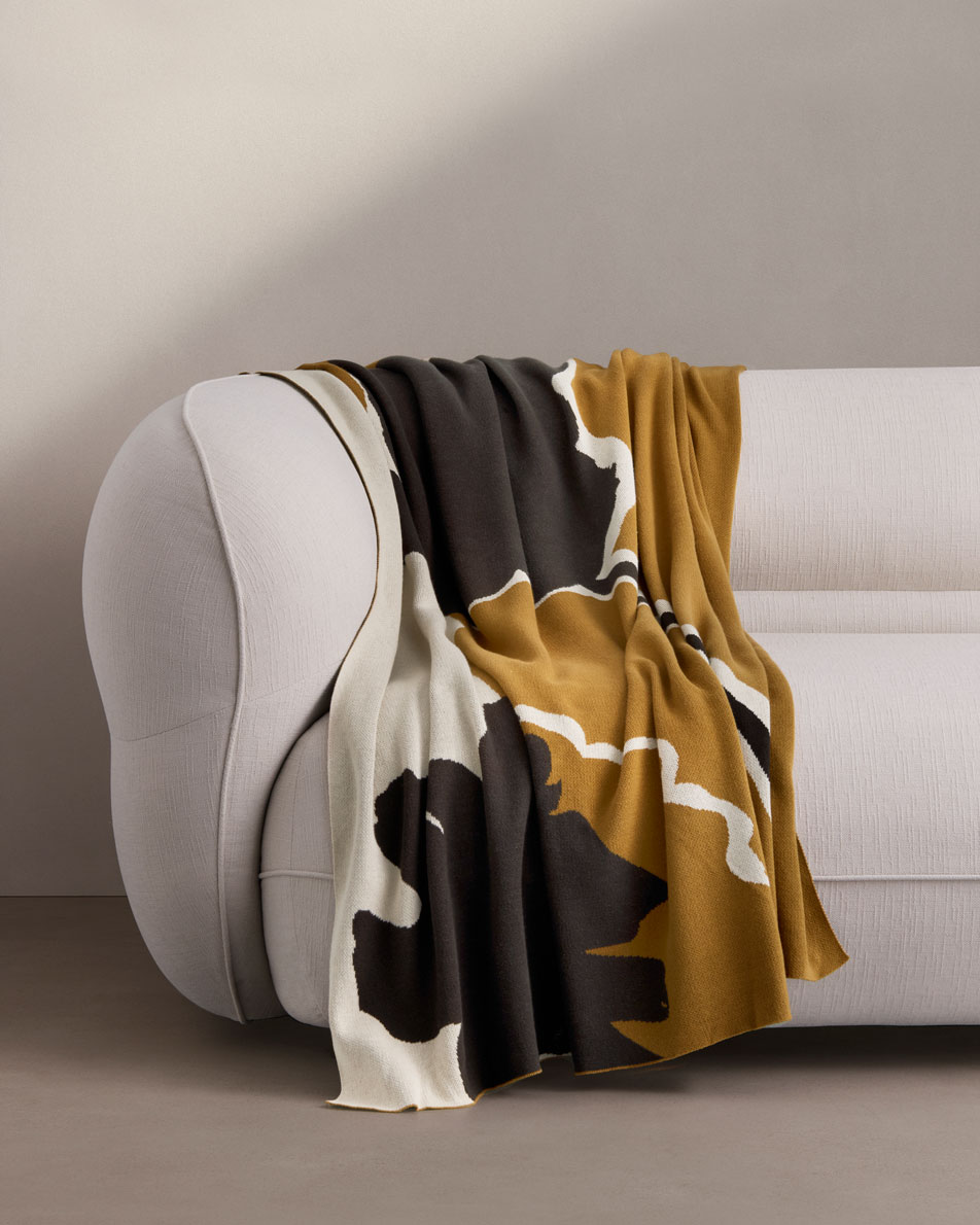 A Perez Throw draped over a neutral fabric sofa