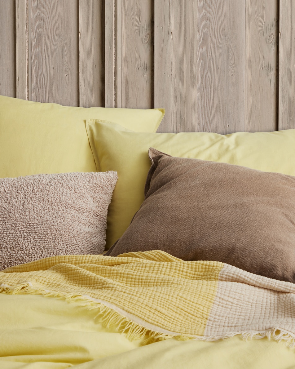 Close-up image of brown cushions on a yellow bed