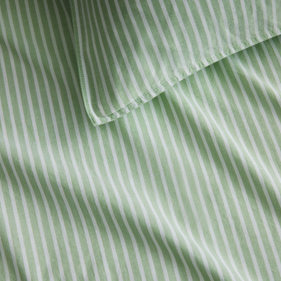 Close up photo of a Reilly Stripe sheet set in snow pea. A matching pillow sits on top.