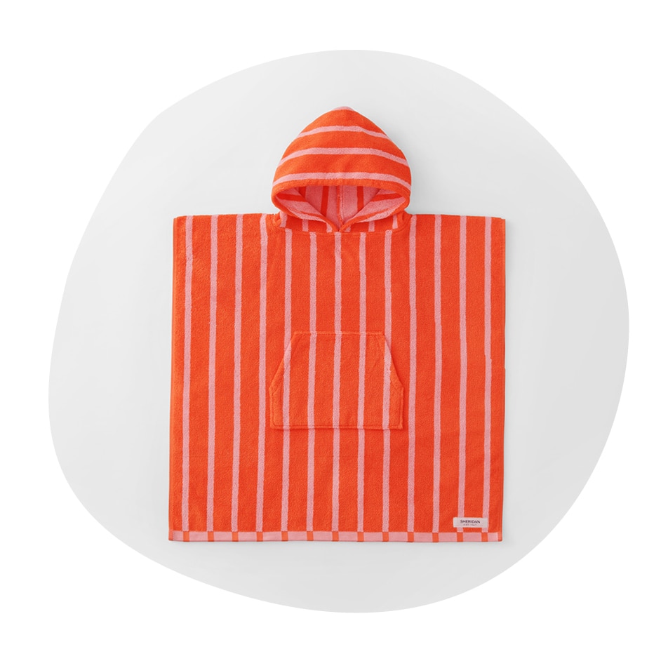 flatlay of sheridan kids pepin hooded poncho. orange-red hooded towel with pink stripes, pocket and hood. the image is in an irregular circle shape, as if drawn by a child.