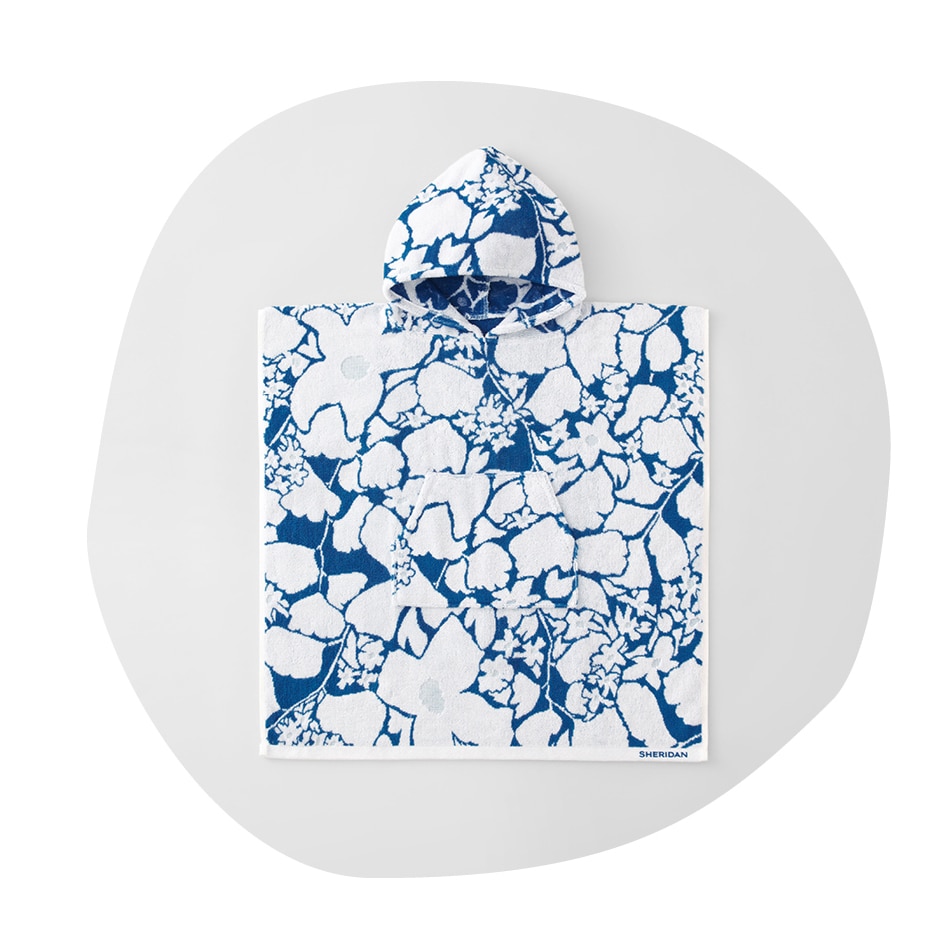 flatlay of sheridan kids nixie hooded poncho. blue hooded towel with white clustered flowers. the image is in an irregular circle shape, as if drawn by a child.
