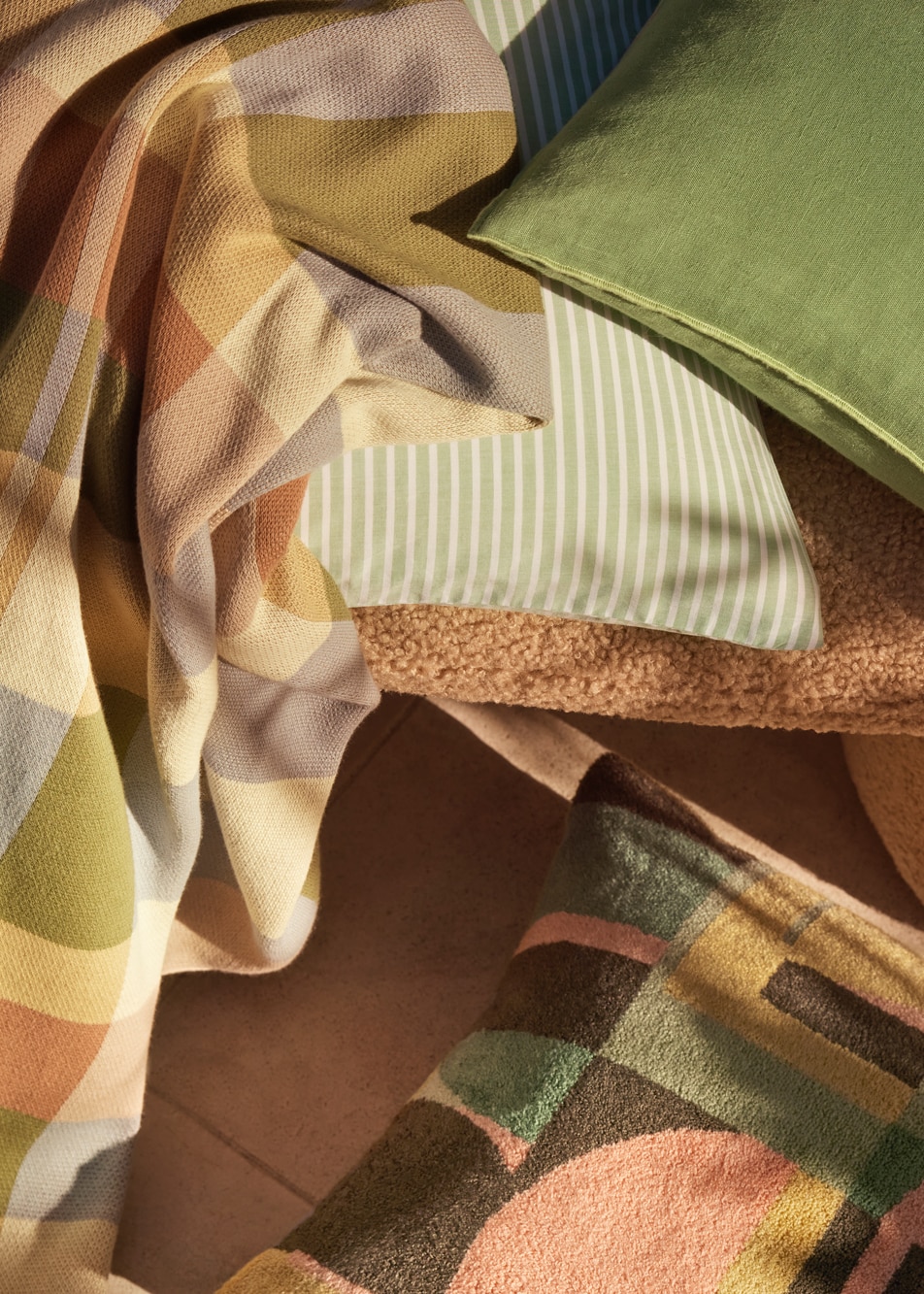 A close-up image of a patterned throw and several cushions scattered around a chair