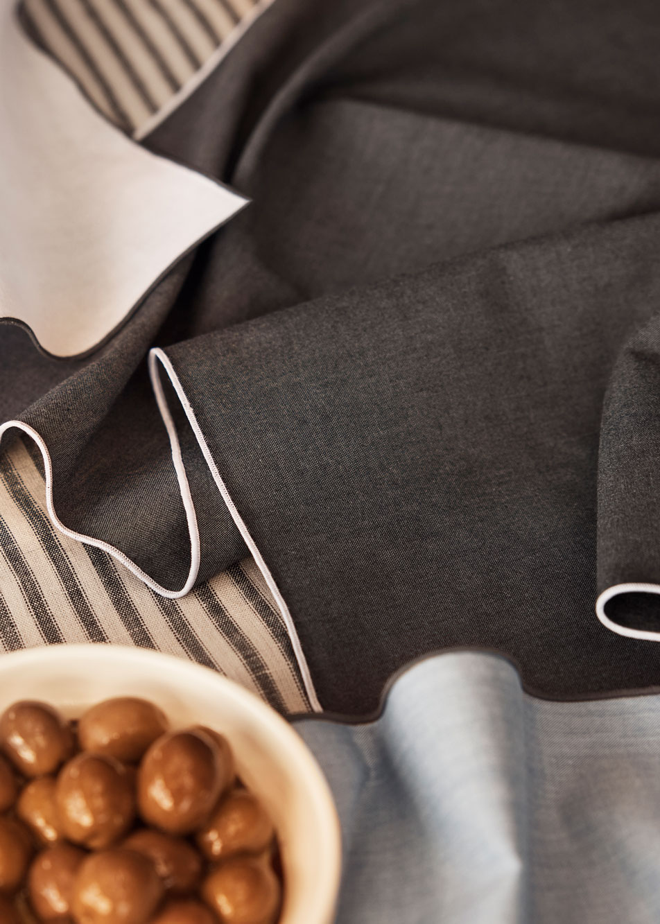 A close-up of different colour fabric napkins with a bowl of olives