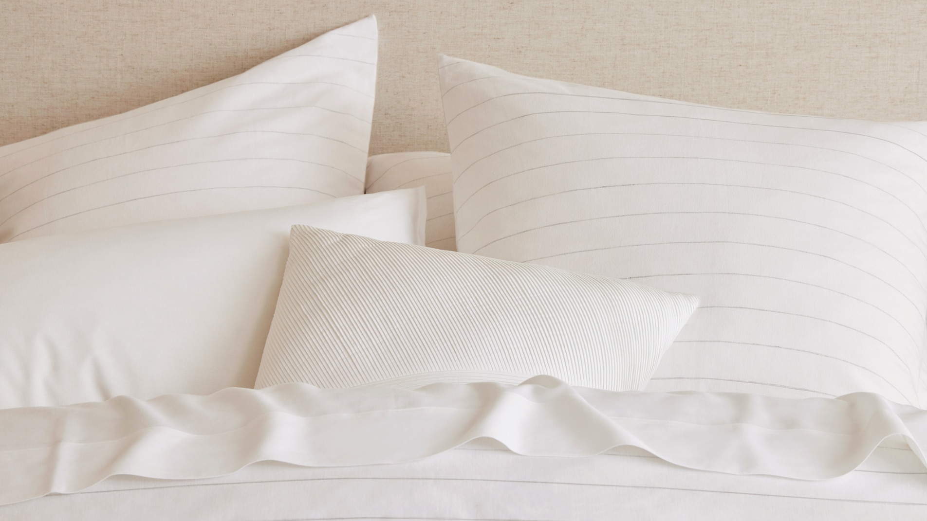 A close up image of layered white pillows and cushions