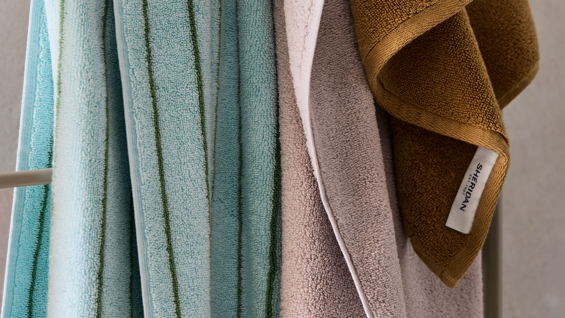 Three Sheridan Aven Australian cotton towels hanging on a metal towel rail
