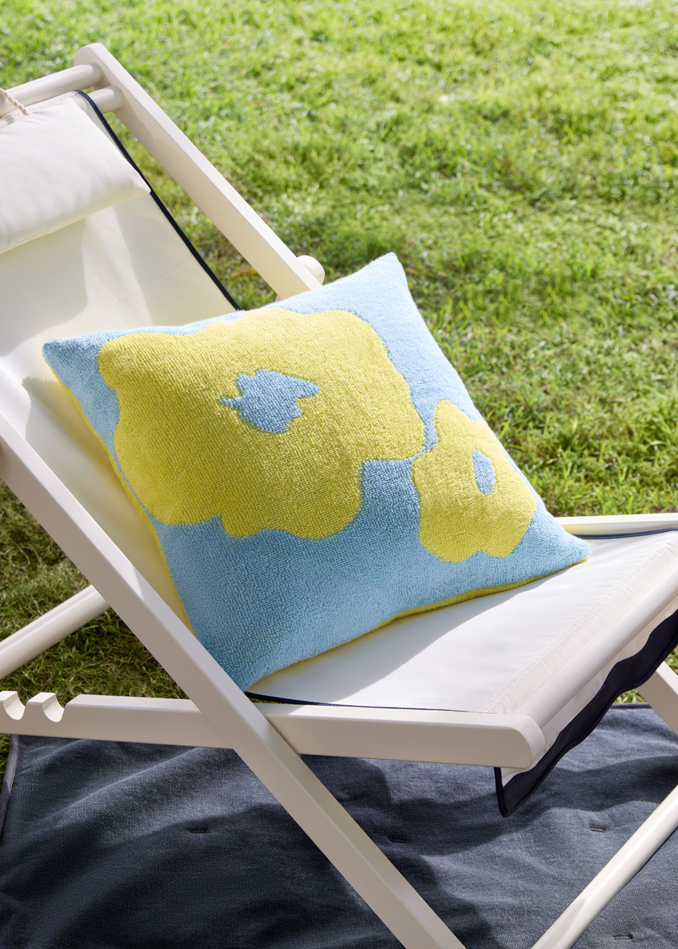 An outdoor cushion sits on a folding chair outside