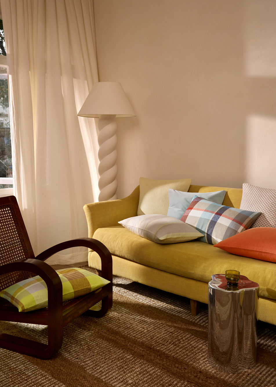 A yellow lounge styled with assorted colourful cushions