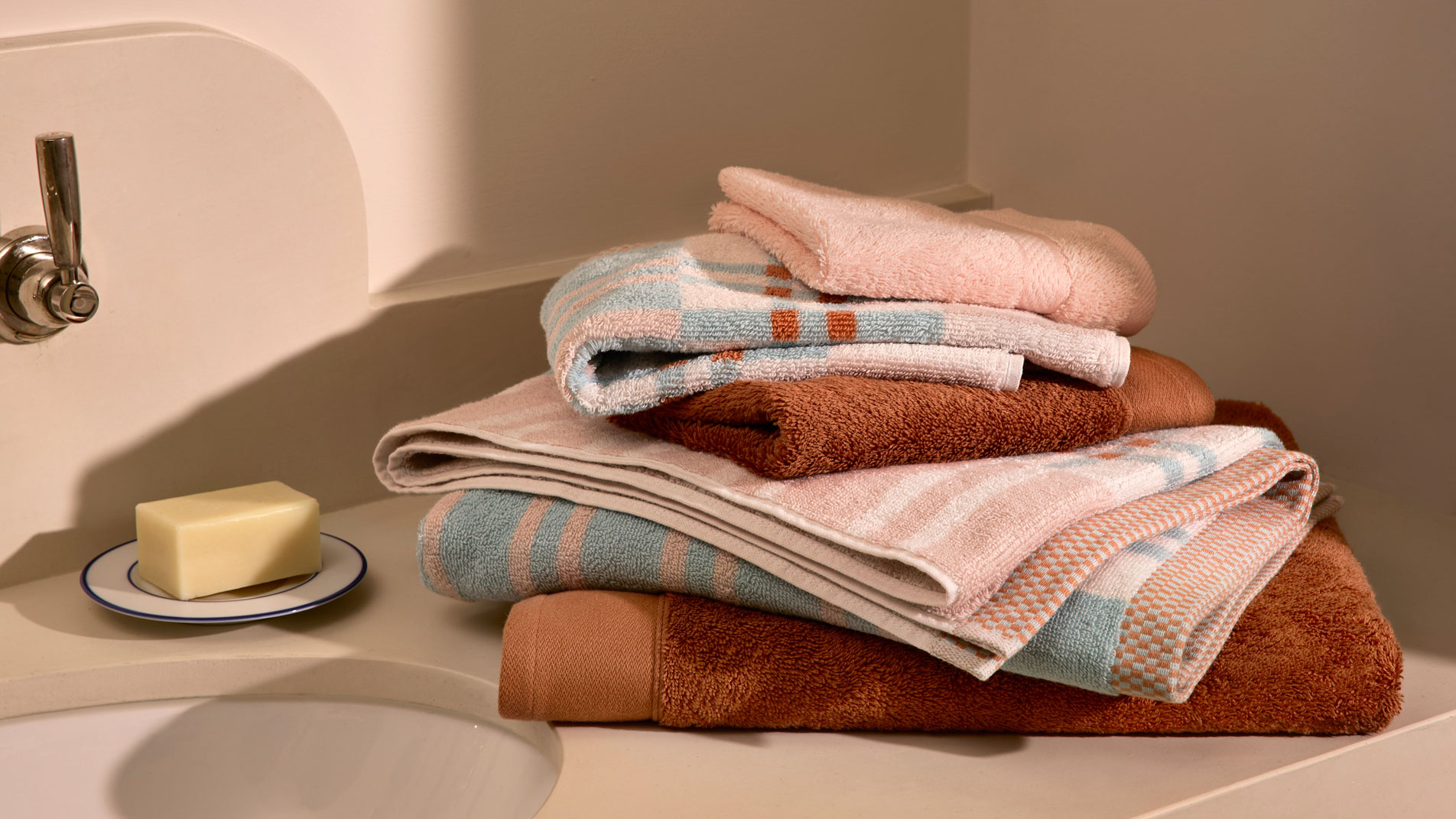 A stack of folded Sheridan bath towels sitting on a bathroom counter