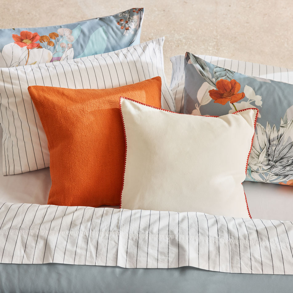 A blue floral print bed with different styles of cushions