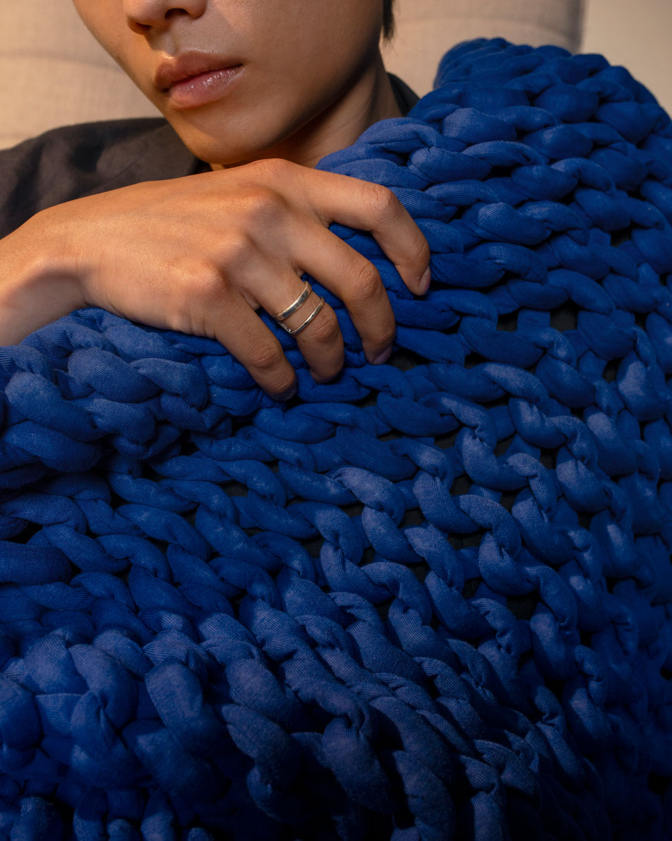 A close-up of a young man's hand gripping a blue weighted blanket