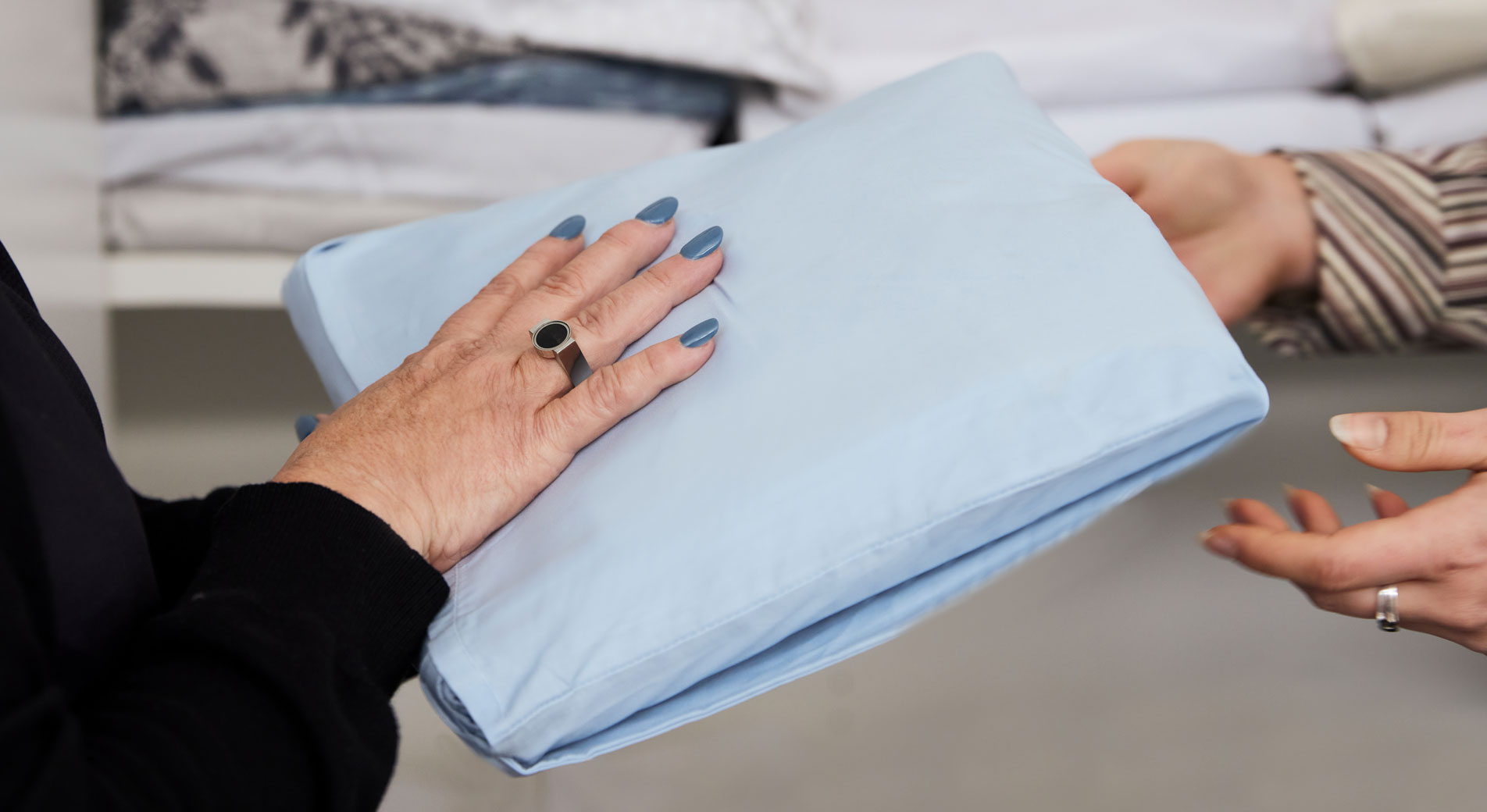 A close-up of two pairs of hands passing a SleepSafe sleep kit between them