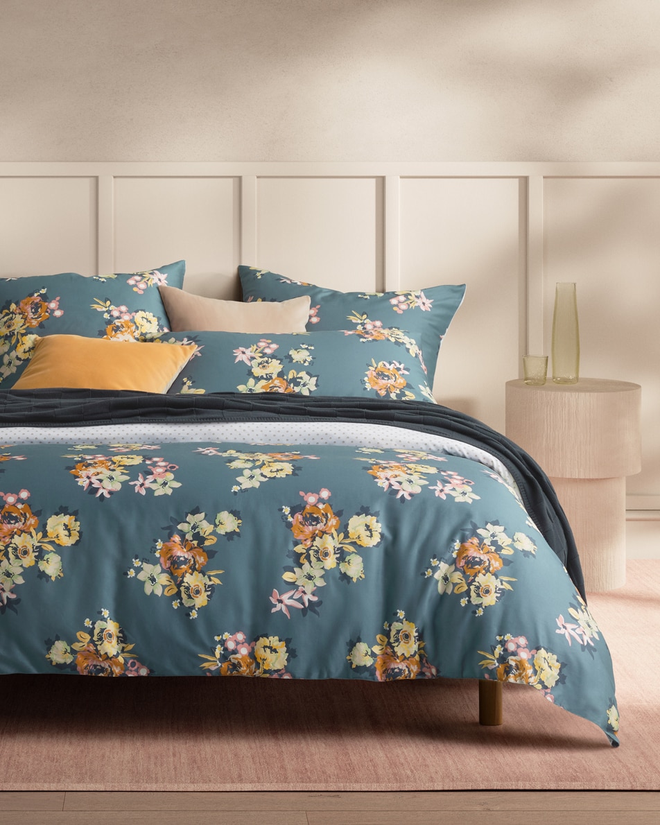 A blue and orange floral bed sits in a neutral bedroom