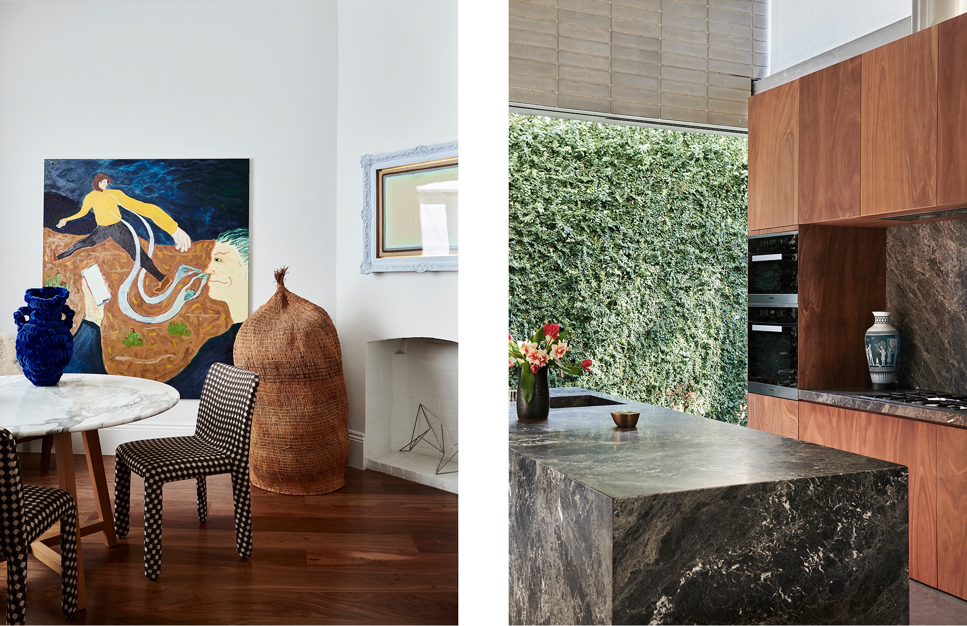 split image. left: marble and wood dining table with blue vase on top, patterned chair tucked in. artwork leans against wall. right: kitchen shot with marble counters and wood cupboards. green plant wall in background.