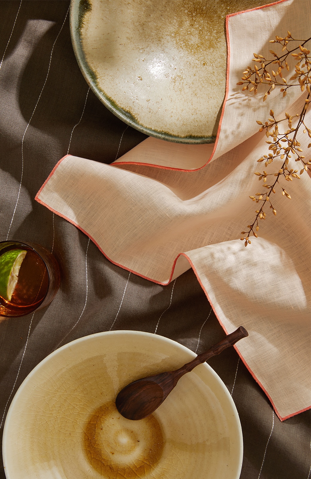 overhead shot of abbotson linen napkins in buff and khaki stripe. set up for dinner party.