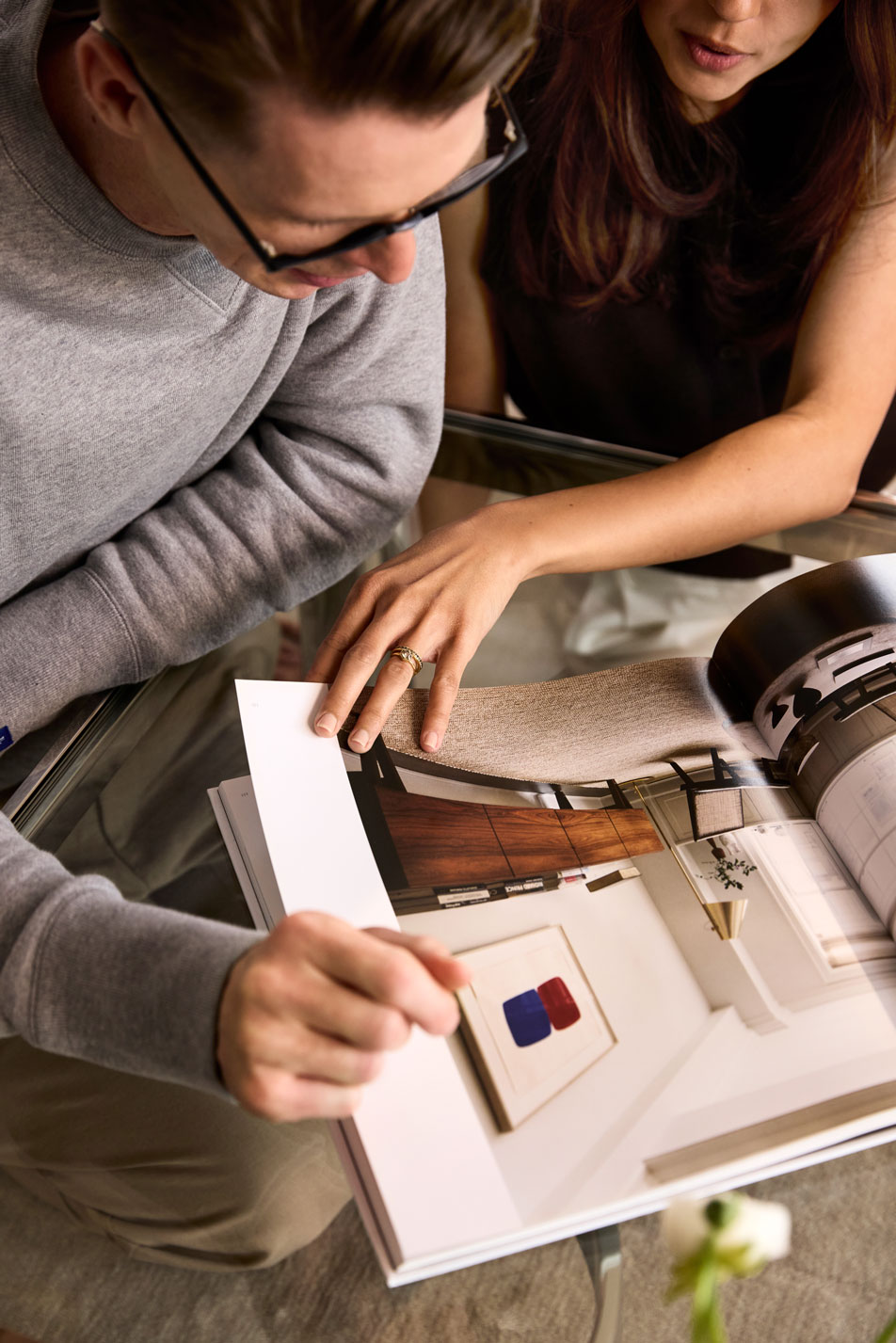 A man and woman sitting side-by-side flipping through an interior design magazine