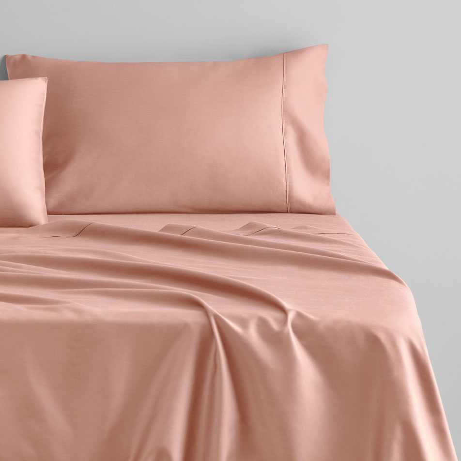 A close-up of a bed with pink sheets and pillowcases.