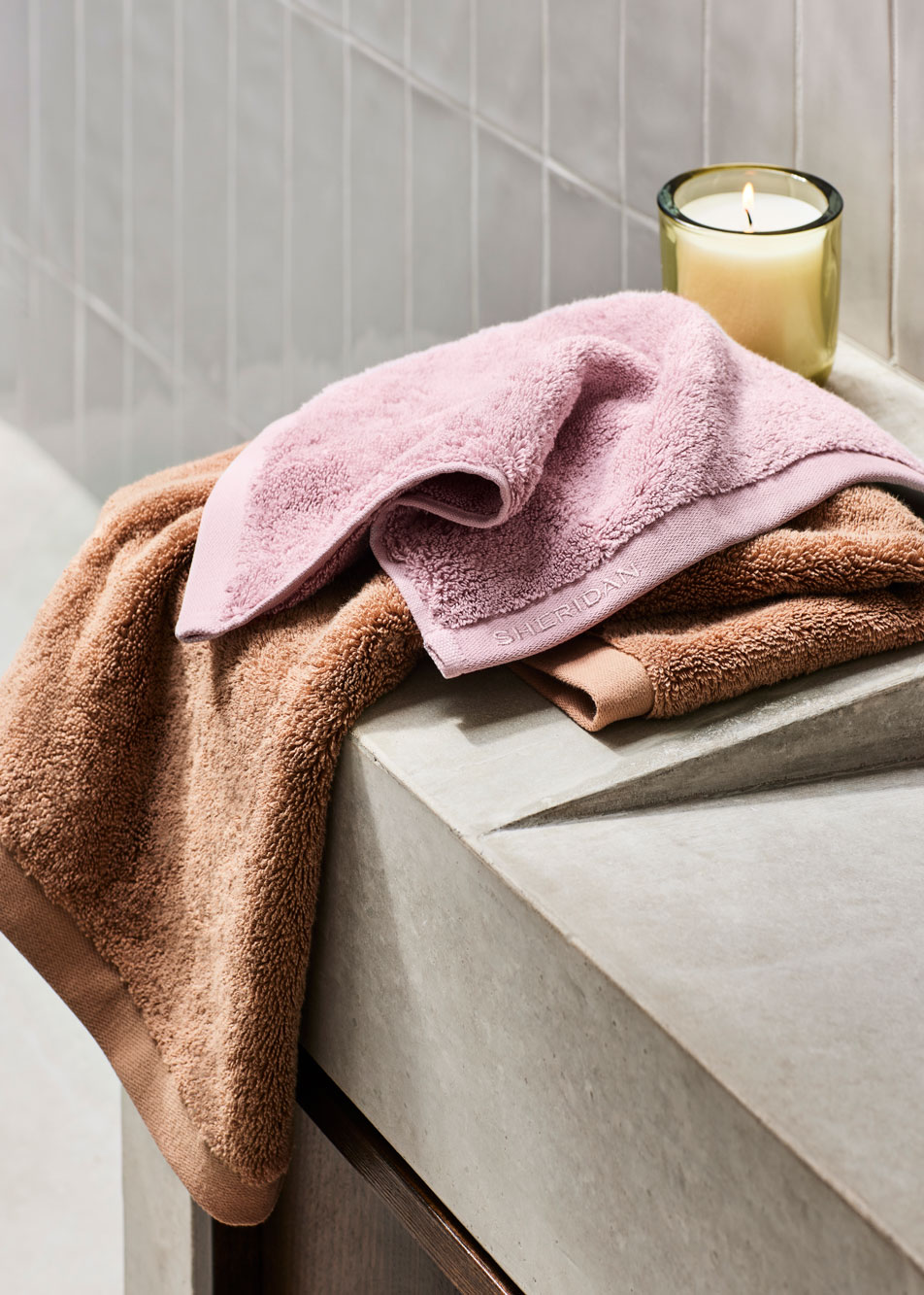 Pink and orange ultimate indulgence towels strewn out on a bathroom counter