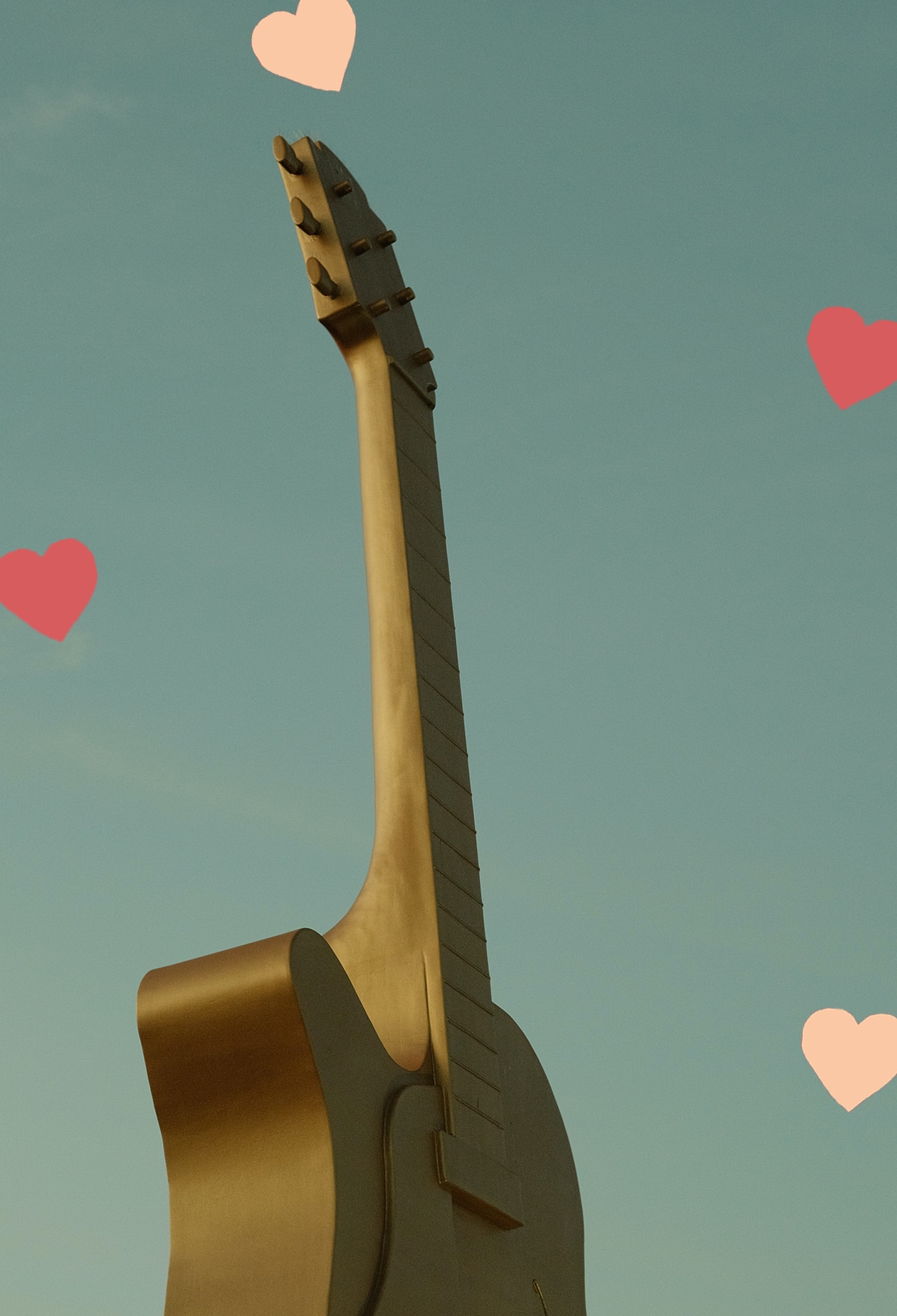 Tamworth's big golden guitar, shot against clear blue sky. Scattered hearts decorate the image.